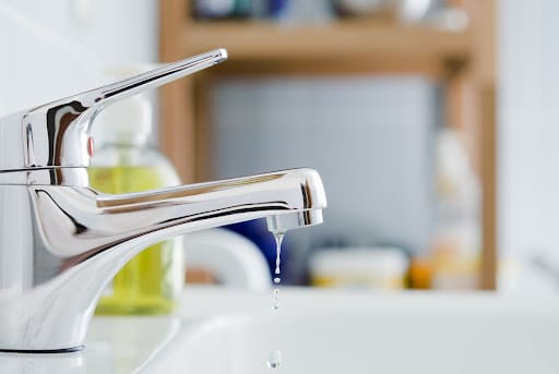 Close up of leaky faucet in bathroom.