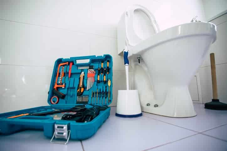 set of tools sitting on the floor near a toilet