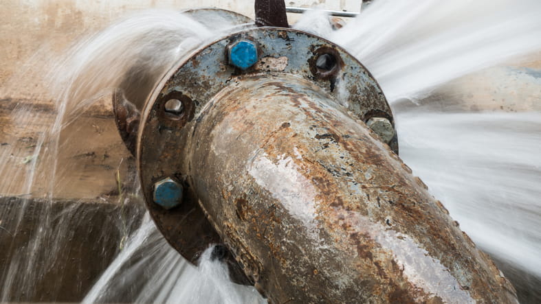 Corroded metal pipe with valve leaking water.