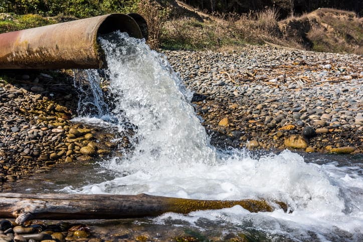 a sewer system pipe gushing out water.