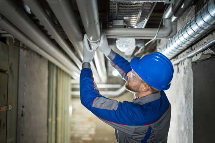 A plumber working on commercial pipes.