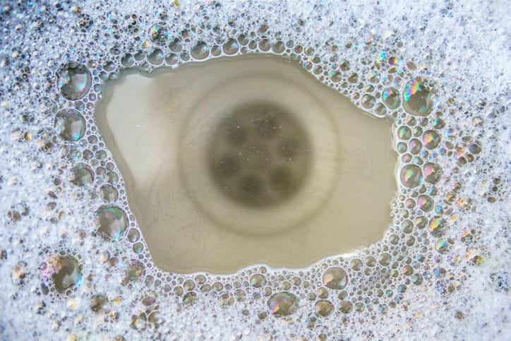 Soapy water backed up in a sink due to a clogged drain. 