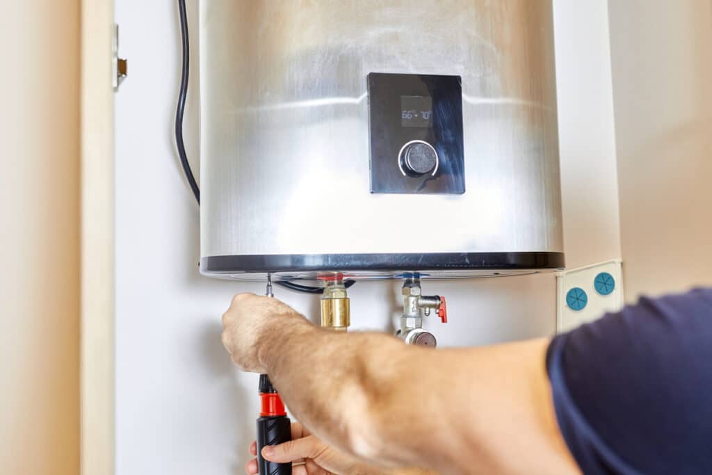 plumber tightening the pipe nut on a water heater in a home.